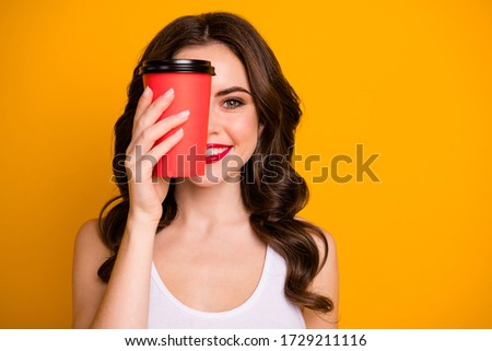 Closeup photo of funny pretty lady hold paper cup takeaway hot coffee hiding half facial expression wear casual white tank-top isolated vibrant yellow color background