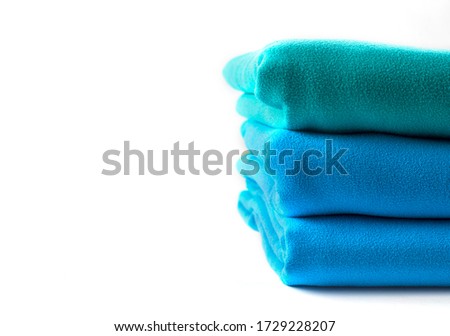 Close up half stack towels green and blue on white background with copy space.