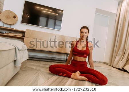 beautiful girl sitting in lotus pose on yoga mat at home on quarantine