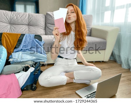 Happy woman with a passport in her hands is sitting next to a suitcase in anticipation of vacation, travel.