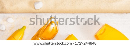 Panoramic shot of top view of yellow sunglasses near sunscreens on white wooden planks and pebble on sand