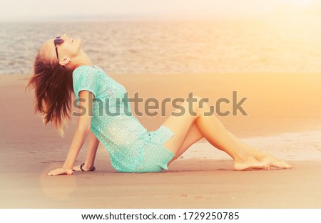 girl sitting on the sand enjoys the rays of the sun