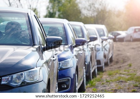 Identical blue cars stand in a row in a Parking lot or market for sale. View of the side mirrors, the Dealership. New car sales. Receiving a car on Commission. Global auto industry crisis Royalty-Free Stock Photo #1729252465