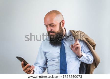 Portrait of stylish bearded businessman in suite on white background while using cellphone and smiling