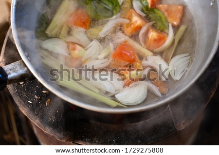 White smoke from cooking and tomato, onion, Lemongrass in stainless pot on stove in countryside kitchen. Thai food. Soft picture