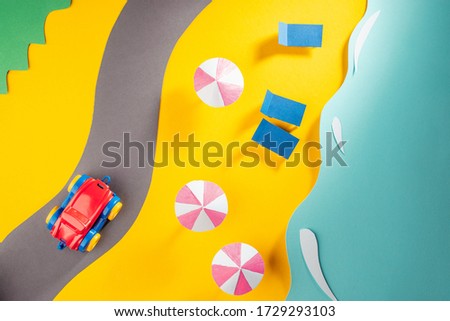 Toy car driving on a paper road along the beachline. Creative artwork by child, beautiful concept for travel and vacation.