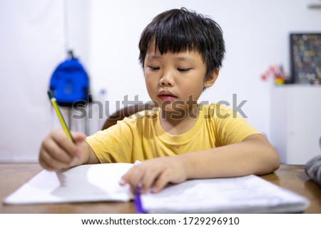 Portrait of little Asian boy doing his homework at home