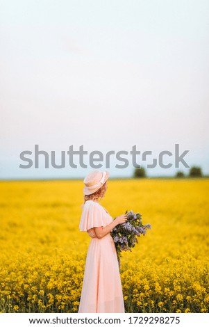 portrait of a young beautiful woman in a hat in spring flowers