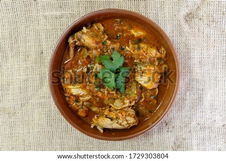 Georgian traditional dish named roast with chicken and herbs in a brown bowl on a burlap background