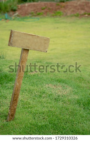 A wooden advertise board mockup in the garden or green field