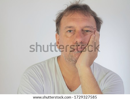 White man with bored expression. White background. Man with grown beard and white shirt. Free space to write.