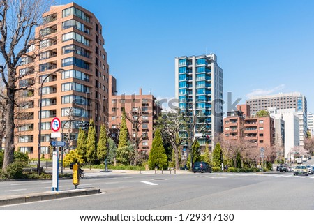 Modern apartment buildings in a residential district in central Tokyo on a clear early spring day. An intersection with traffic lights is in foreground.