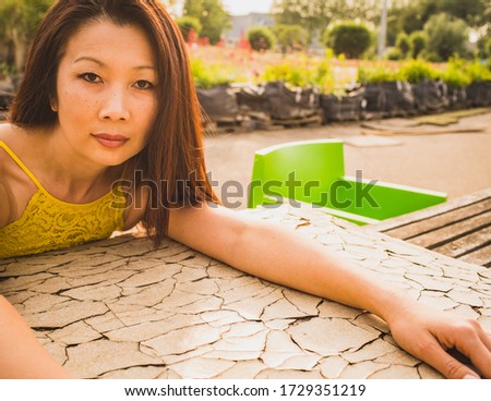 Asian female look. A 40 year old lady sits in a summer garden and looks at the camera.