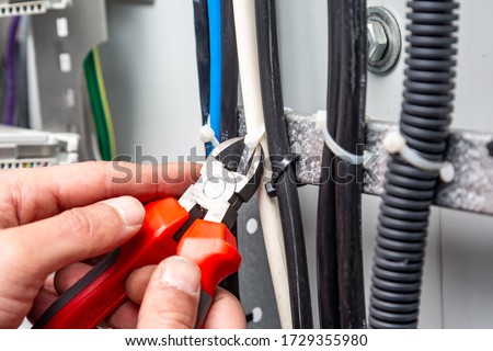 Hands with wire cutters cut the cable ties. Horizontal orientation. Royalty-Free Stock Photo #1729355980