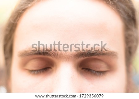 Fused eyebrows of a young man with unibrow of European appearance. The grooming on the face. Men's cosmetology. Soft focus.