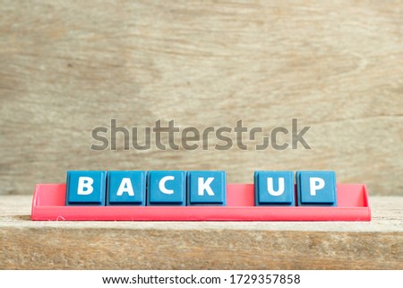 Tile letter on red rack in word back up on wood background