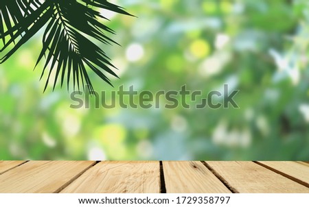silhouette of plam tree and empty wood floor with bright bokeh of nature park background,product display montage.