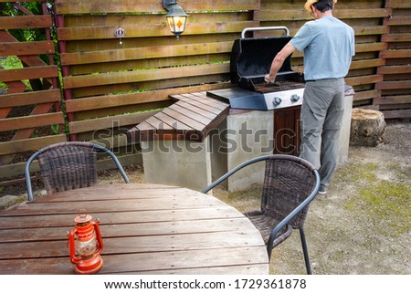  Man cleaning barbecue in his back garden, preparation for frying meat. Royalty-Free Stock Photo #1729361878
