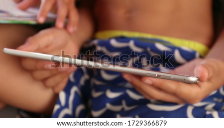 
Kid hand watching content online holding tech gadget tablet