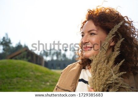 Close up of beautiful lady holding dry field grass and smiling stock photo. Website banner