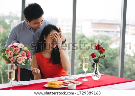 Valentine festive anniversary date at restaurant concept. Man couple hand hold a romantic flower bouquet surprise gift give it to girlfriend. Casual style hotel dinner table.