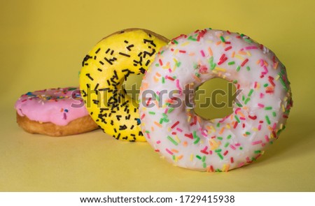 Three multi-colored donuts on a yellow background, a picture on the screen saver, suitable for presentations or design of postcards