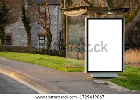 Empty bus stop in town with blank mock up vertical billboard for advertising.