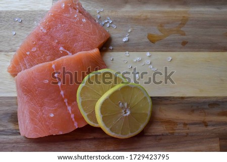 Freshly sliced salmon with rock salt and freshly sliced lemon on a wooden texture background