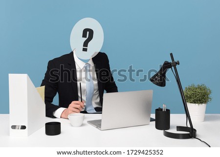 Businessman with question mark for head busy working at office desk looking at laptop computer