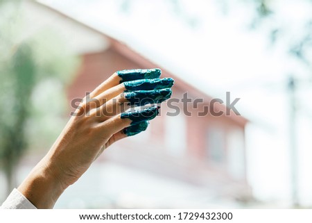 Listen To Your Art. Close up of woman hand dirty with acrylic paint. Female artist using hand while adding blue color. Creative finger painting. Horizontal shot. Selective focus