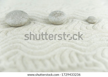 Zen garden. Pyramids of white and gray zen stones on the white sand with abstract wave drawings. Concept of harmony, balance and meditation, spa, massage, relax