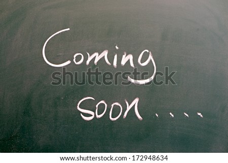 hand writing "coming soon" on blackboard 