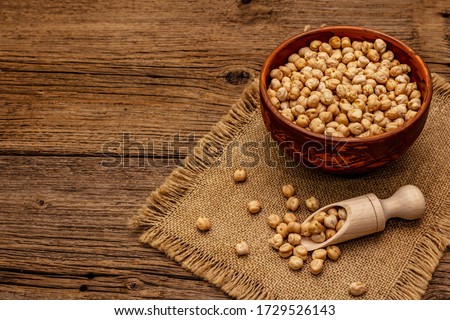 Dry chickpea in ceramic bowl on old wooden boards background. Traditional ingredient for cooking hummus. Middle Eastern and Mediterranean cuisine Royalty-Free Stock Photo #1729526143