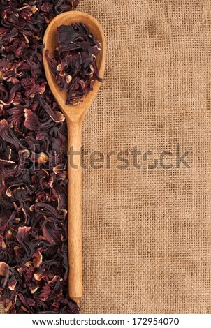 Wooden spoon with dried hibiscus, lies on the background burlap