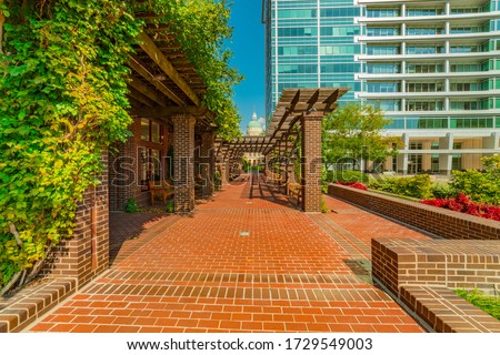 A brick path of a local public park, Hudnut Commons, leads to the copper domed capitol building with an arbor leading the way, in Indianapolis, Indiana. 