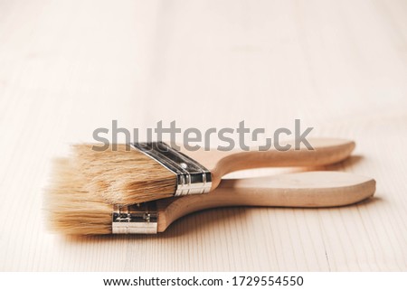 Two paint brushes with a wooden handle and natural bristles on a wooden background. Repair concept. Copy, empty space for text