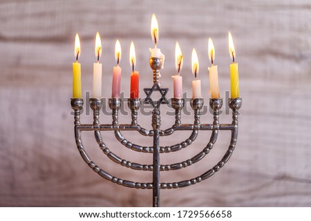 Silver Hanukkah menorah with candles on a light wooden background. Holiday concept