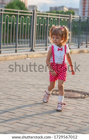 Little girl, 3-4, with tails running down the road