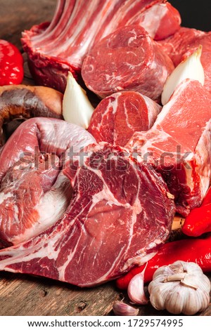 A lot of raw fresh juicy fermented meat. Beef uncooked steaks on a wooden table. Vertical view