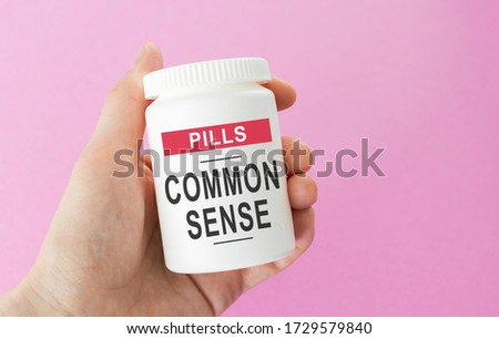 Hand holds a jar of pills, the inscription: COMMON SENSE Royalty-Free Stock Photo #1729579840