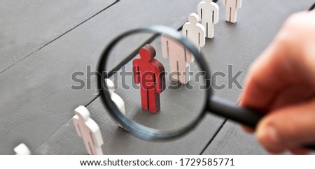 The view through the magnifier on the one wooden red person between other people Royalty-Free Stock Photo #1729585771