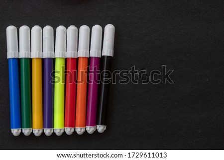 Colourful pens lying on black background