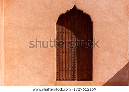 Traditional Arabian architecture, muslim style wooden door and red clay wall Royalty-Free Stock Photo #1729612159