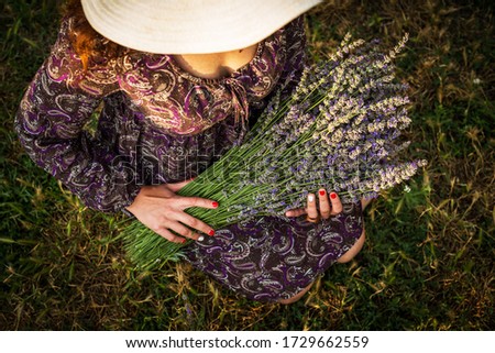 a girl with a large bouquet of lavender flowers in a hat holding a bouquet in her hands top view not visible face
