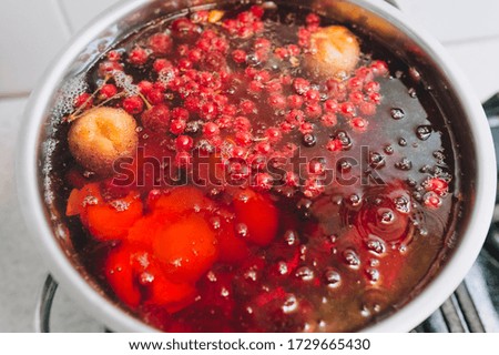 Cooking a delicious compote of apricot, apples, cherries, raspberries. Fresh fruits are boiled in boiling water in a metal pan on the stove. Photography, concept.