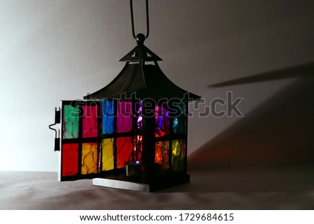 lantern in the form of a house with colorful bright Windows and an open door with a burning candle on a white background