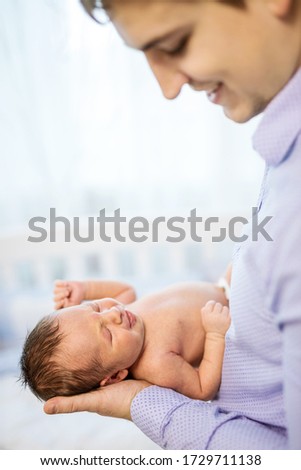 Newborn baby boy and his happy dad. Baby in focus.