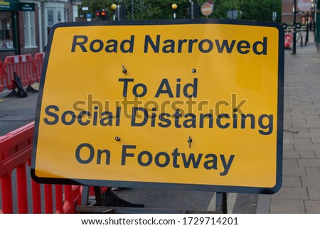 A sign explaining that the road is half-closed to allow space for social distancing on the pavement.
