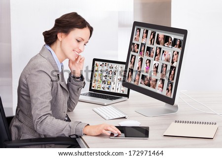 Portrait Of Happy Young Businesswoman Browsing Pictures On Computer