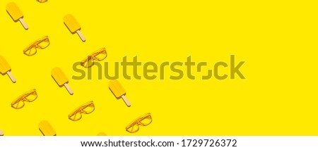 Creative minimal border frame of popsicles and sunglasses on abstract yellow background with copy space